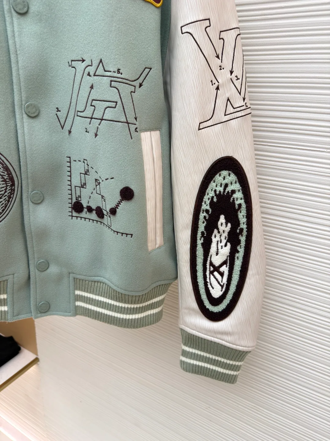 LOUIS VUITTON letter pattern patch printed color block baseball jersey ●Original version: 38999 purchase and development ●Item number: 1681672-D15 ●Fabric: sheep wool fabric ●Technology: printing production ●Color: green ●Version: fitted version ●Weight: about 1220 grams ●Size: 46-48-50-52 ●Description: This jacket is made of high-quality wool blended fabric, which is soft to the touch and has excellent warmth retention. The overall design adopts a lapel design, and the collar, cuffs and hem are all ribbed, with moderate elasticity, comfortable to wear and not easy to deform. The main part uses multi-color splicing technology. The gray and white splicing lines are smooth and natural, showing superb tailoring technology. The patterns on the chest and sleeves are embroidered and appliquéd, with distinct layers and a strong three-dimensional effect. Multi-colored silk threads are interwoven during the embroidery process to ensure that the pattern is clear and durable. The buttons of the jacket are made of metal, with a smooth surface and not easy to fade. The splicing of the shoulders and sleeves adopts seamless technology, with smooth and natural lines without excess threads. The overall workmanship is fine, and every stitch is even and neat, reflecting the high-quality production process. The overall wiring is straight and delicate, the fabric is comfortable and soft, and the color is consistent without color difference. It can be matched with the same style to create a fashionable look and control various occasions. Customized accessories, complete with three standards, same style for men and women!